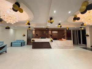 a lobby with a bar and a blue couch and chandeliers at Hotel Mikado Palace in Gurgaon