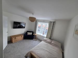a bedroom with a bed and a chair and a window at Lower Townhouse, Exeter in Alphington
