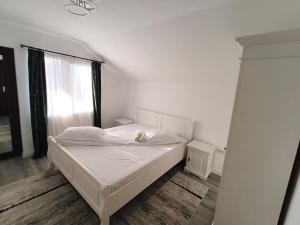 a bedroom with a white bed and a window at Casa Drăgan in Novaci-Străini