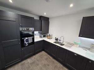 a kitchen with black cabinets and white counter tops at Lower Townhouse, Exeter in Alphington +8 photos