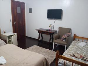 a bedroom with a desk and a chair and a tv at Marins Pousada - Campos do Jordão in Campos do Jordão