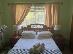 ein Schlafzimmer mit einem Bett mit weißer Bettwäsche und einem Fenster in der Unterkunft DKC Accommodation in Sutherland