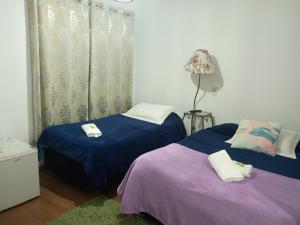 a bedroom with two beds and a lamp at Marins Pousada - Campos do Jordão in Campos do Jordão