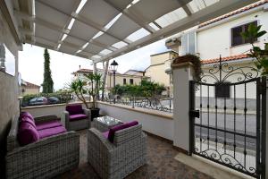 a patio with wicker chairs and purple cushions on a balcony at Pepe'Accommodation in Parghelia
