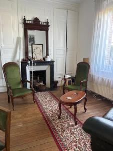a living room with two chairs and a table and a fireplace at La briqueterie in Bourseville