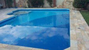 a blue swimming pool with a reflection of the sky at Recanto Praia Peruibe in Peruíbe