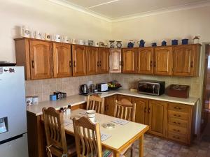 eine Küche mit Holzschränken und einem Tisch mit Stühlen in der Unterkunft DKC Accommodation in Sutherland + 13 Fotos