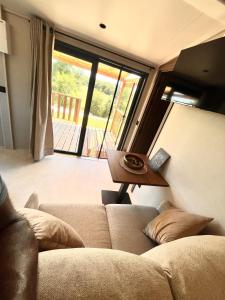 a living room with a couch and a table at O'BARA Lodge - Tiny House - Jardin et climatisation in Druillat