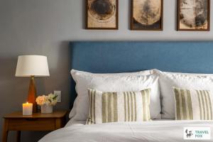 a bedroom with a blue headboard and a bed with pillows at Charlotte's Cottage, a Charming Cotswolds Getaway in Adlestrop