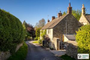 an old stone building on a street in a village at Charlotte's Cottage, a Charming Cotswolds Getaway in Adlestrop
