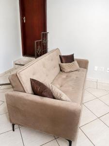 a couch with two pillows on it in a living room at Studio aconchegante com ar-condicionado e Smart TV in Bauru
