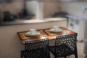 a wooden table with two cups and plates on it at Studio aconchegante com ar-condicionado e Smart TV in Bauru +33 photos