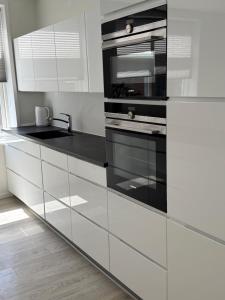 a kitchen with white cabinets and black appliances at Lille Vedelsborg 1 in Vejle