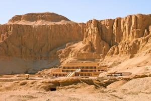 a building in the desert next to a mountain at Vipxplor Travel in Luxor