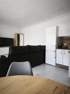 a living room with a black couch and a kitchen at Apartamentos Joli in Olivares de Duero