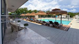 a swimming pool with chairs and umbrellas next to a resort at HILLIUS Resort in Solotvyno