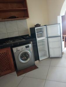 a kitchen with a washing machine and an open refrigerator at Beach front Spacious Studio in Malindi