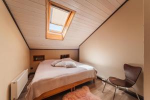 a attic bedroom with a bed and a window at Zaļais Stūrītis - Semi-Detached Holiday Home with Private entrance & Indoor Sauna in Liepāja