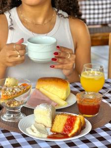 a woman sitting at a table with a plate of food at Pousada Estância Mineira in Guapé
