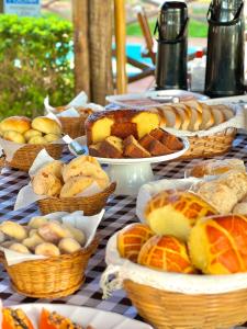 a table topped with baskets of bread and pastries at Pousada Estância Mineira in Guapé