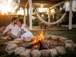 a man and a woman sitting next to a fire at Pousada Estância Mineira in Guapé