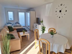 a living room with a table and a clock on the wall at Kleinstadt-Fritz in Radeburg +5 photos