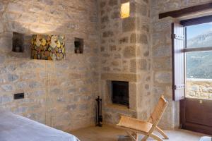 a bedroom with a stone wall with a fireplace at Petra & Fos Boutique Hotel & Spa in Neo Itilo