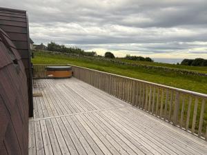 a wooden deck with a fence on a house at Bromach Lodge & NEW HOT TUB in Latheron
