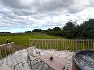 a wooden deck with chairs and a hot tub at Bromach Lodge & NEW HOT TUB in Latheron
