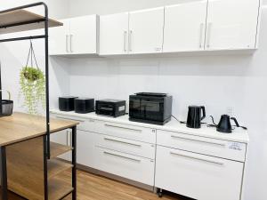 a white kitchen with white cabinets and a microwave at ヴィラ砂時計超豪華大型貸切別荘九十九里海歩3分寝室5つペット可サウナ本格カラオケグランドピアノ全自動麻雀bbq焚き火 in Kujukuri