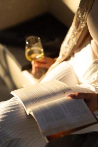 a woman reading a book with a glass of wine at MaDaM Essence in Nei Poroi