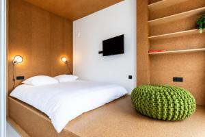 a bedroom with a white bed and a green ottoman at Hotel BonBon & BonBon Budget in Rotterdam