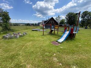 a playground with a slide in a field at Apartmány U Fibichů in Orlické Záhoří 