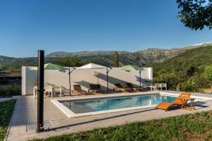 a villa with a swimming pool with mountains in the background at Tiny House Kety in Zrmanja Vrelo