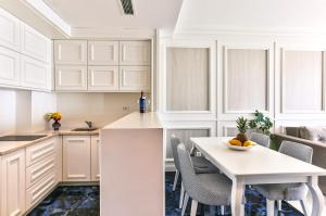 a kitchen with white cabinets and a white table and chairs at Azure Coast Deluxe Residence - Budva Seafront Living Suites in Bečići