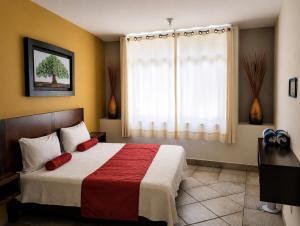 a bedroom with a bed with red pillows and a window at Hotel Tepoztlán in Tepoztlán +25 photos