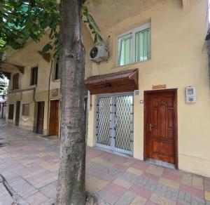 a building with a wooden door next to a tree at Sweet Home in Pogradec