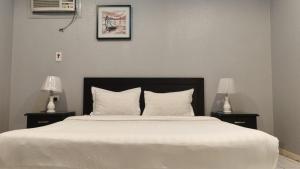 a bedroom with a large white bed with two lamps at مساكن صفوه الديار in Abha +3 photos