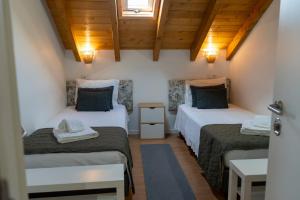 two beds in a room with wooden ceilings at Casa do Chafariz in Cercal