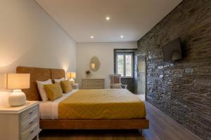 a bedroom with a bed and a stone wall at Feel Discovery Casa Fonte do Lagar in Desejosa +38 photos