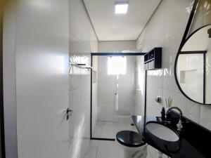 a bathroom with a sink and a toilet and a mirror at Sobrado Matinhos 480 m da praia l novo l central 3quartos in Matinhos +99 photos