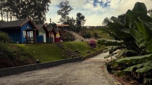 a row of colorful houses on a gravel road at Chale verde Aconchegante com lareira no bosque e estacionamento grátis in Extrema +19 photos