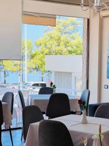 a room with tables and chairs and a large window at Hotel Lungomare in Vlorë