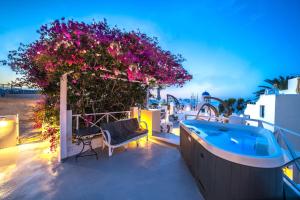 a villa with a swimming pool and a garden with flowers at Santorini Paradise Cave Houses in Oia