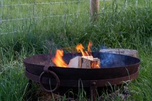 a fire pit with flames in it in a field at Castor in Abergele