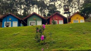 a row of colorful houses on a grassy hill at Chale Amarelo Aconchegante com lareira no bosque e estacionamento grátis in Extrema