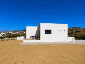 a white house with a bench on the side of it at Villa relax glinado luluvo in Glinado Naxos