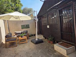 a patio with a couch and an umbrella at The Cozy Cabin in Pretoria