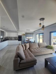 a living room with a brown couch and a kitchen at Villa relax glinado luluvo in Glinado Naxos