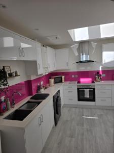 a kitchen with white cabinets and pink walls at Number 1 School Path in Coalbrookdale